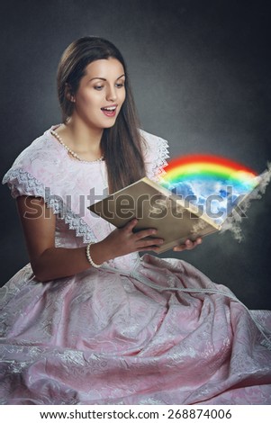 Beautiful woman with surprise expression opens a magical book . Surreal and fantasy 