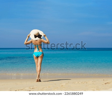A beautiful woman in a swimsuit posing on a Thai beach at summer. Concept of holiday, vacation, traveling and resort.