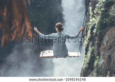 Beautiful woman swings near waterfall in the jungle of Bali island, Indonesia.