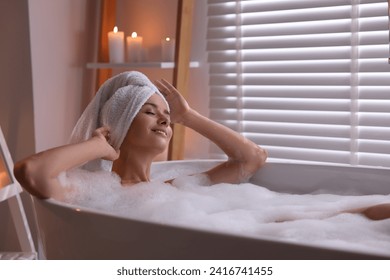 Beautiful woman taking bath in tub with foam indoors. Romantic atmosphere - Powered by Shutterstock