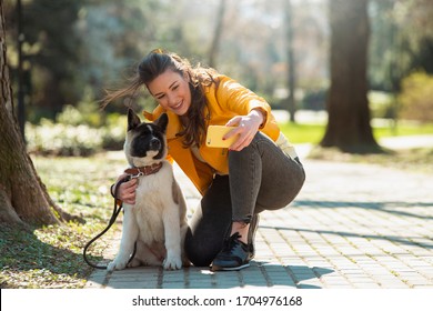 Beautiful woman taking photo with her dog