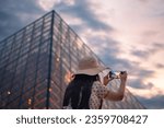 A beautiful woman  taking pictures in front of The Louvre Museum, one of the world