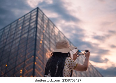 A beautiful woman  taking pictures in front of The Louvre Museum, one of the world's largest museums and a historic monument. A central landmark of Paris, France.