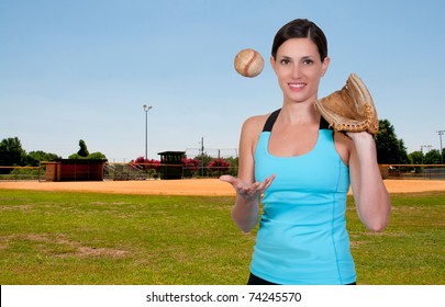 A Beautiful Woman Throwing A Baseball Into The Air At A Ball Field