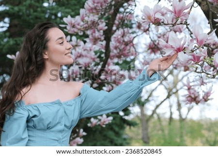 Beautiful woman touching blossoming magnolia tree branch on spring day