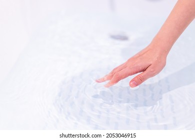 Beautiful Woman Touching On The Surface Of Water In Bathtub To Check The Water Temperature Before Get In The Bath. Wellness And Hydro Therapy Concept.