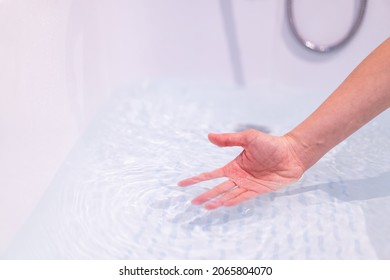 Beautiful Woman Touching On The Surface Of Water In Bathtub To Check The Water Temperature Before Get In The Bath. Wellness And Hydro Therapy Concept.