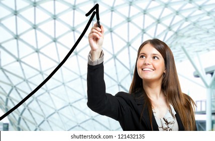 Beautiful woman tracing a rising arrow, representing business growth