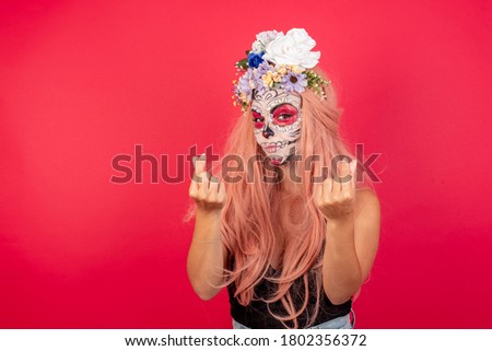 beautiful woman with traditional mexican face painting, wears wreath made of aromatic flowers doing money gesture with hands, asking for salary payment, millionaire business