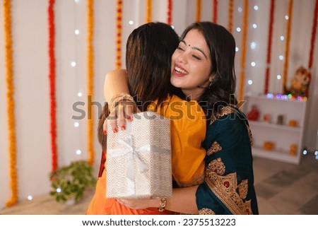 Beautiful woman in traditional wear surprising her friend with a Diwali gift - festive vibe, Diwali celebration. Friends celebrating Diwali festival together at home - ethnic wear, festival of ligh...