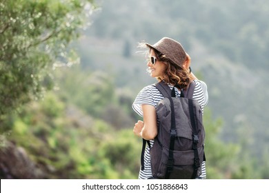 beautiful woman traveler with backpack and in hat on wood background. She is smiling and cheerful, she walks and feels happy and free.
