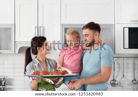 Beautiful woman treating her family with freshly oven baked buns in kitchen