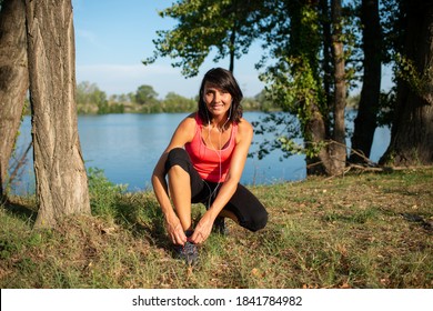 schöne Frau, die sich beim Laufsportfitness und Outdoor-Sport in einem Park auf der Landschaft am Schnelace bindet