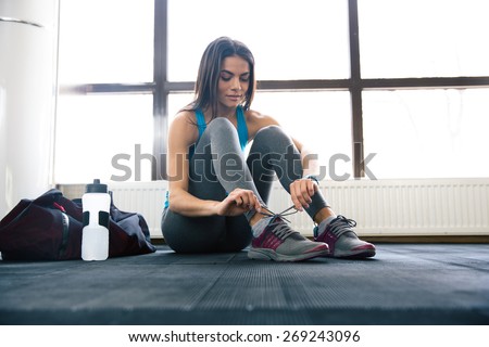 Beautiful woman tying shoelaces at gym 