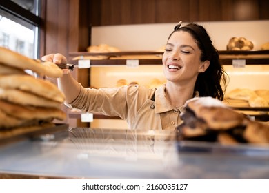 Beautiful Woman In Uniform Working In Bakery Shop And Selling Pastry To The Customer.