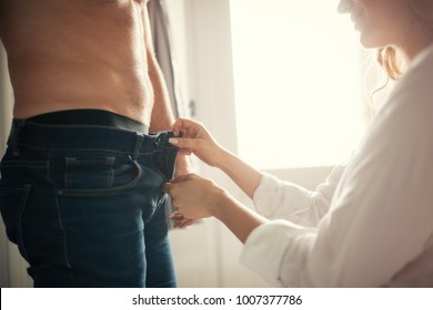 Beautiful woman unzipping shirtless handsome boyfriend's jeans