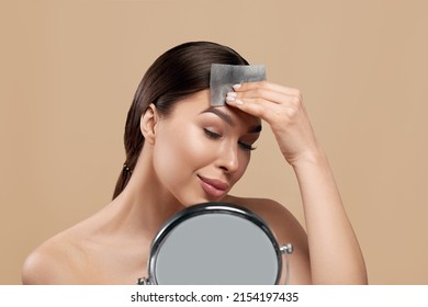 Beautiful woman using facial oil blotting paper. Woman with perfect makeup. Beauty concept. Cosmetology, cosmetics. Facial treatment.