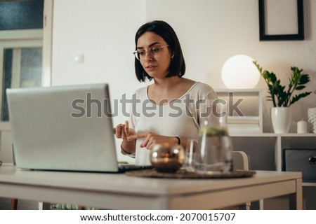 Beautiful woman using a laptop for an online meeting with her colleagues while working remotely from home