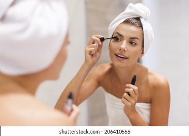 Beautiful woman using mascara in bathroom - Powered by Shutterstock