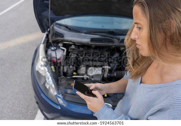 Beautiful woman using smart\
phone calling or texting car insurance company after automobile\
breakdown for road assistance .Repair and accident trouble concept\
lifestyle.