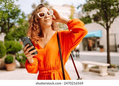 Beautiful woman using smartphone at summer street in the European city. Blogging, technology, lifestyle, travel, tourism, active life. - Powered by Shutterstock