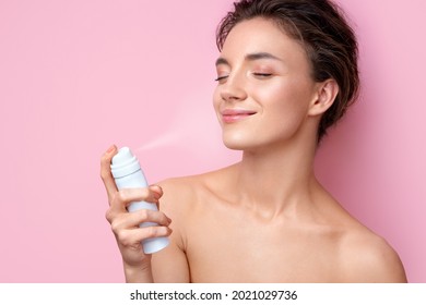 Schöne Frau, die Spray mit Thermalwasser verwendet. Foto von Frau auf rosafarbenem Hintergrund. Beauty- und Hautpflegekonzept
