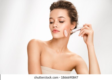 Beautiful Woman Using Stone Facial Roller On White Background. Beauty And Skin Care Concept