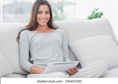 Beautiful Woman Using A Tablet Sat On A Couch