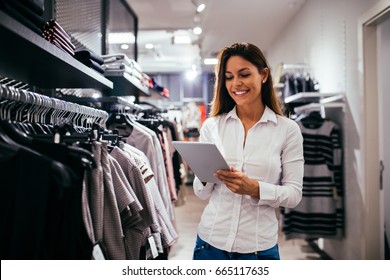 Beautiful woman using tablet while working in the store. - Shutterstock ID 665117635
