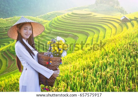 beautiful woman with Vietnam culture traditional dress, Ao dai and holding lotus on Rice fields on terraced of Mu Cang Chai, YenBai, Rice fields prepare the harvest at Northwest Vietnam.