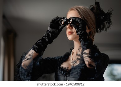 Schöne Frau in schwarzvintage Kleid, die eine Opera-Brille im Inneren hält