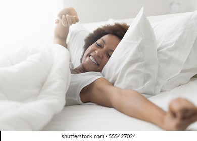 Beautiful woman waking up in her bed, she is smiling and stretching - Powered by Shutterstock