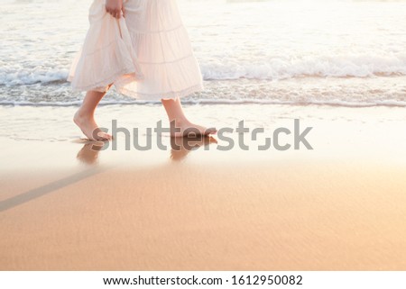 Beautiful woman walk on the beach with sea surf at sunset