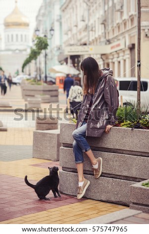 beautiful woman walking with a cat in the city in the bright day, mild toning