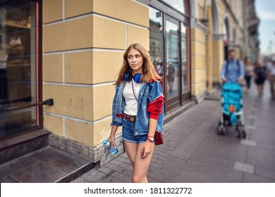 Beautiful Woman Is Walking Down Crowded Street. Young Caucasian Female 25 Years Old In Shorts Walks In City.