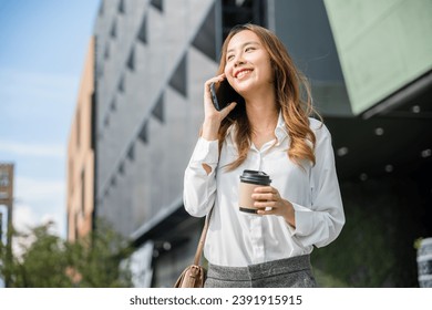 Beautiful woman walking outside in street and calling talking on mobile phone outdoors near office, portrait lifestyle businesswoman with bag cell to customer while holding coffee paper cup takeaway - Powered by Shutterstock