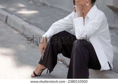 A beautiful woman walking in the street of the city. A business woman looking sidesways. the female wearing the style basic outfit,  black trousers and white shirt
