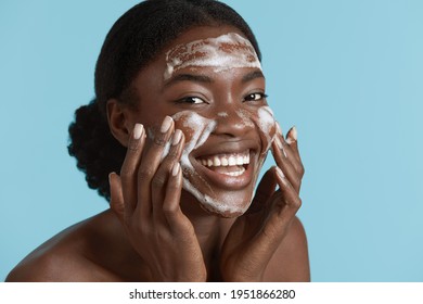 Beautiful Woman Wash Her Face With Cleansing Face Foam. Smiling Young Girl Looking At Camera. Concept Of Face Skin Care. Isolated On Blue Background. 