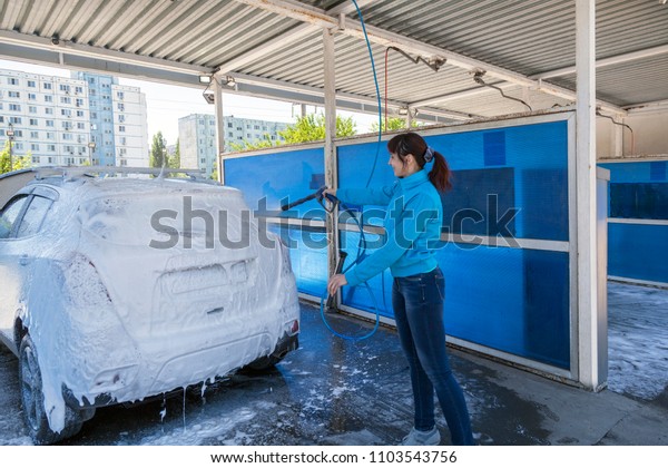 Beautiful woman washes car on car wash, car\
wash self-service