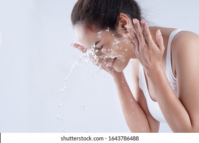 Beautiful Woman Washing Her Face In A White Background Studio