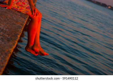 beautiful woman watching the sunset while sitting near the water.