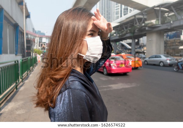 Beautiful woman wearing anti dust mask\
protect air pollution and pm 2.5 on street\
city