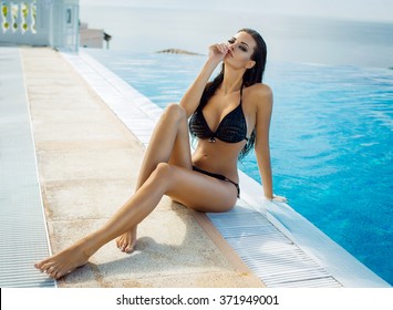 Beautiful woman wearing black bikini by the pool in summer scenery