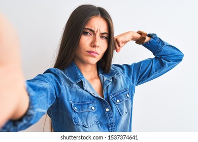 Beautiful Woman Wearing Denim Shirt Make Selfie By Camera Over Isolated White Background Strong Person Showing Arm Muscle, Confident And Proud Of Power