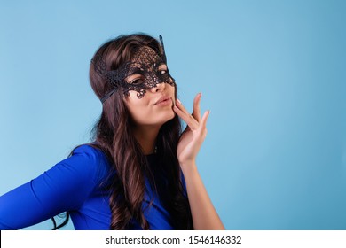 beautiful woman wearing elegant black mask isolated over blue