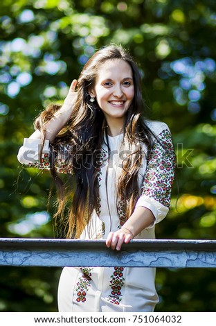 Beautiful woman wearing an embroidered dress poses in the park
