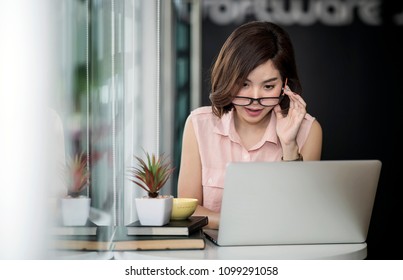 Beautiful woman wearing eyesglasses looking at screen while working with laptop in coffee shop
