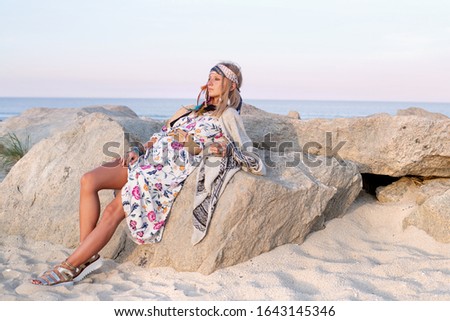 Beautiful woman wearing long dress and accessories boho style. Attractive bohemian style girl on the beach