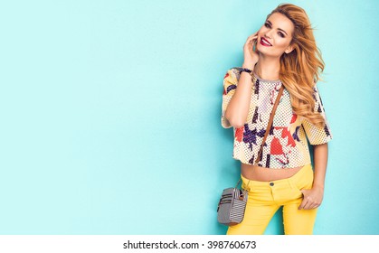 Beautiful Woman Wearing Nice Clothes, Handbag Posing On Turquoise Background. Fashion Spring Photo. Bright Colors