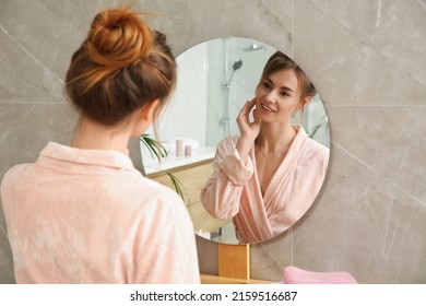 Beautiful woman wearing pink bathrobe in front of mirror at home - Powered by Shutterstock